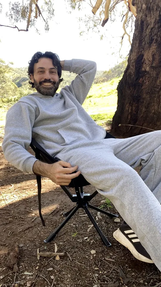 Creator relaxing in a camping chair under a gum tree